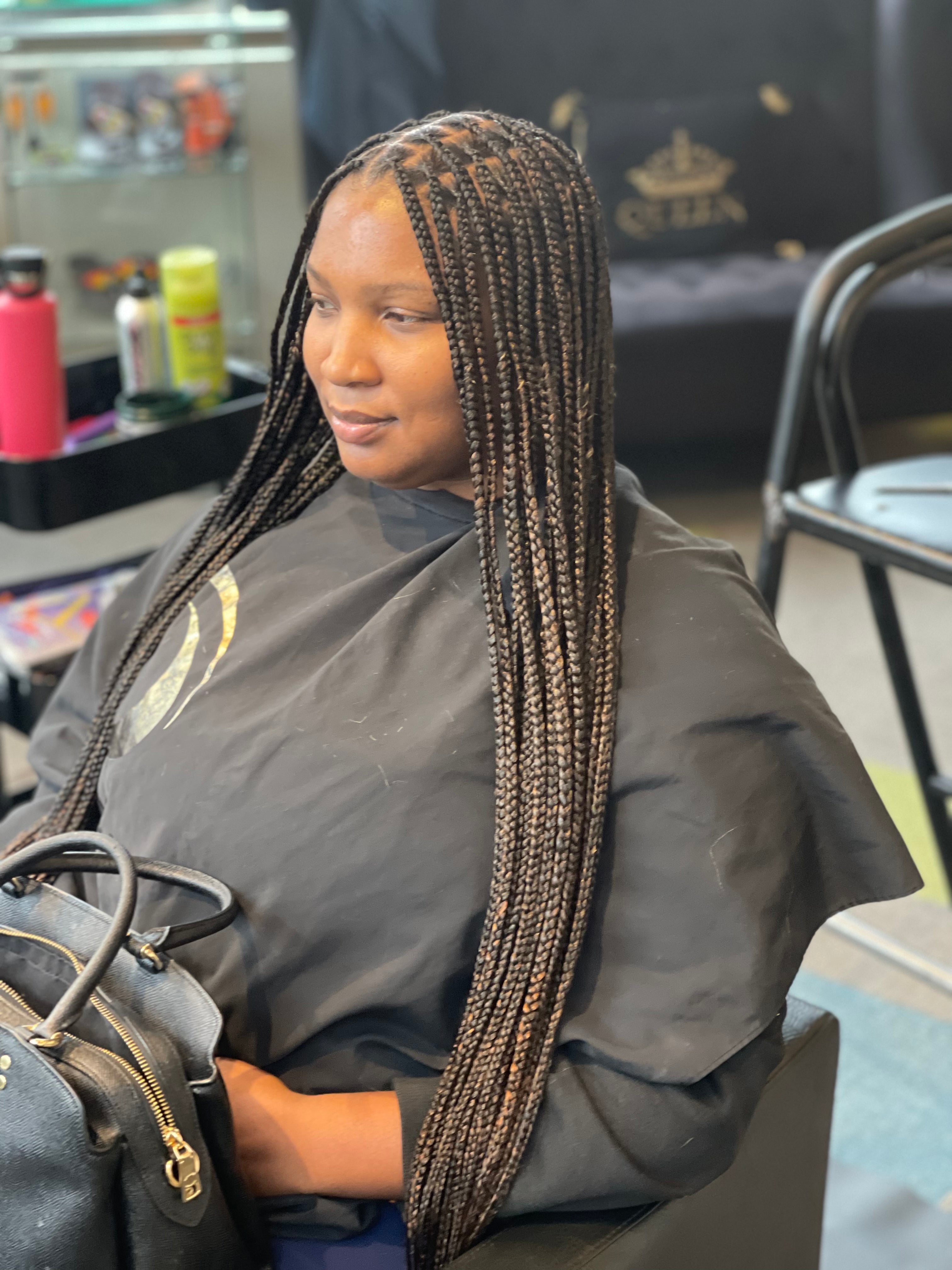 A woman with medium waist length knotless braids at Oumy Beauty Studio.