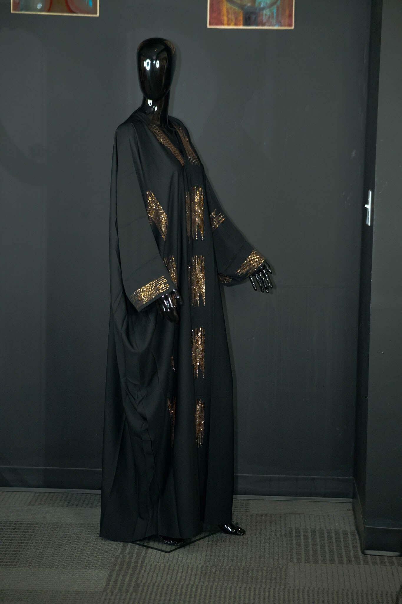 Black abaya with intricate multicolored patterns, crafted from silky fabric, showcased by Oumy Beauty Studio