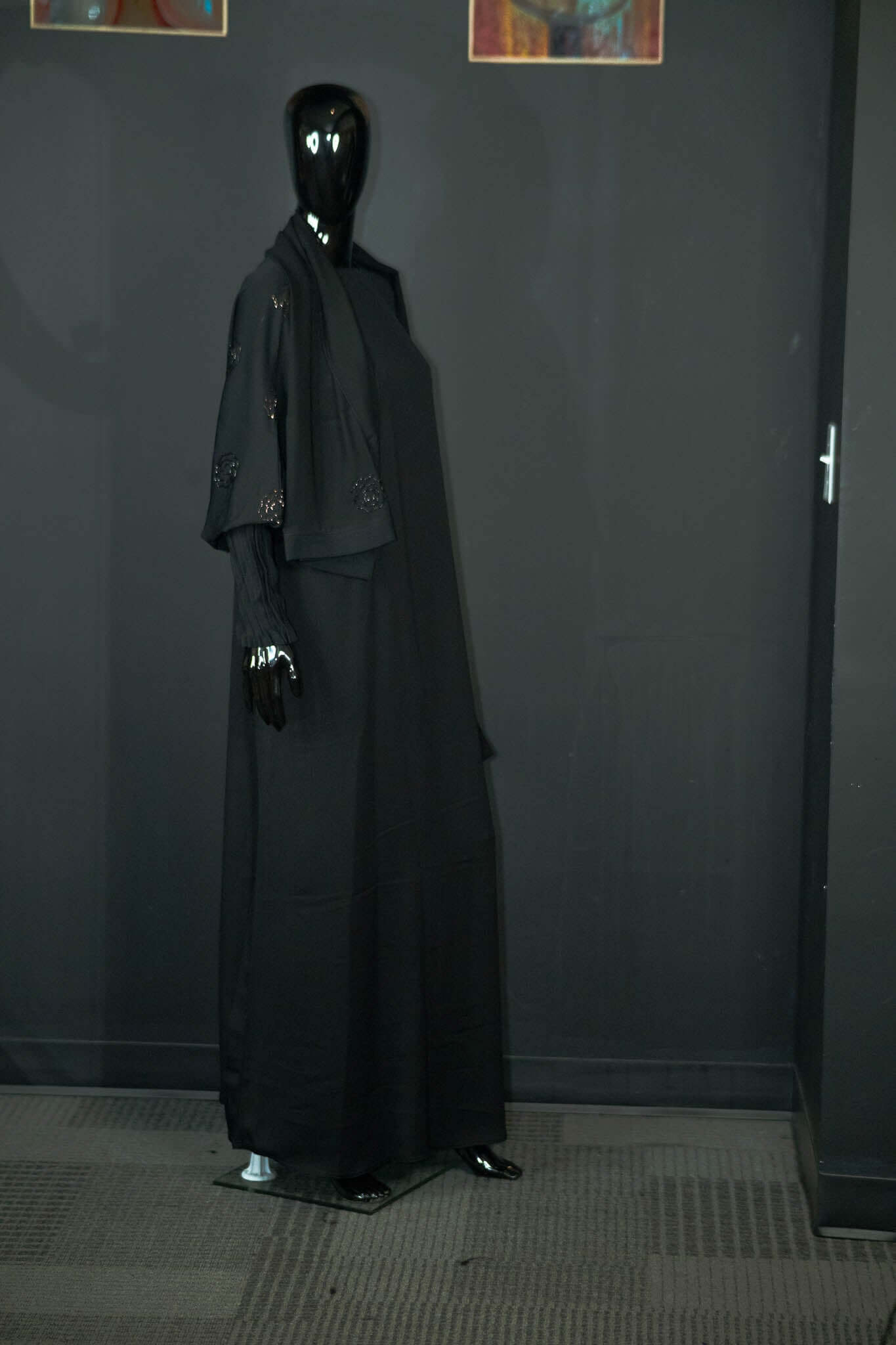 Black abaya dress with intricate designs on mannequin at Oumy Beauty Studio.