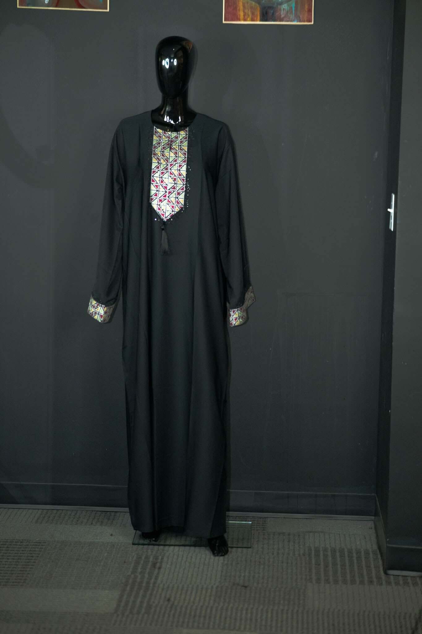 Black abaya with intricate multicolored patterns, designed by Oumy Beauty Studio, featuring silky fabric and elegant design.