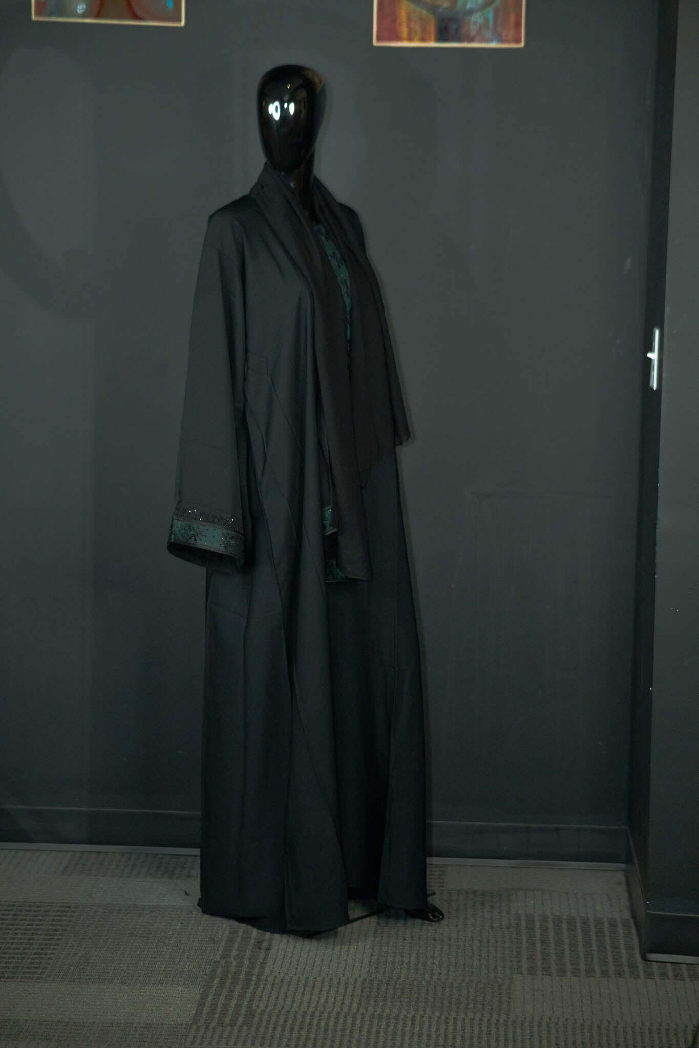 Black abaya with intricate multicolored designs on display by Oumy Beauty Studio.