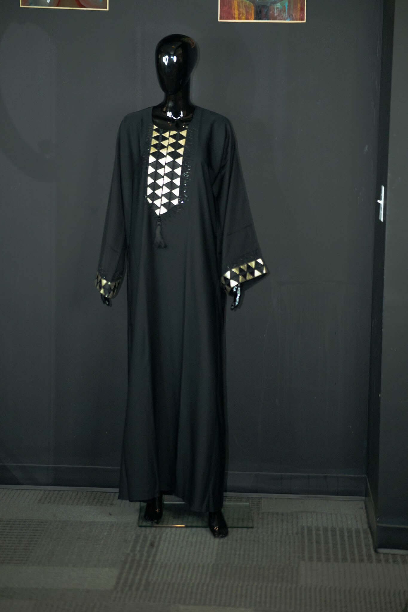 Elegant black abaya with intricate geometric designs on mannequin at Oumy Beauty Studio.